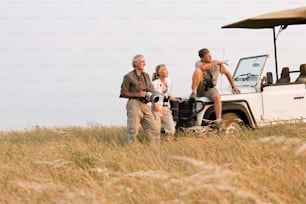 a group of people standing next to a safari vehicle