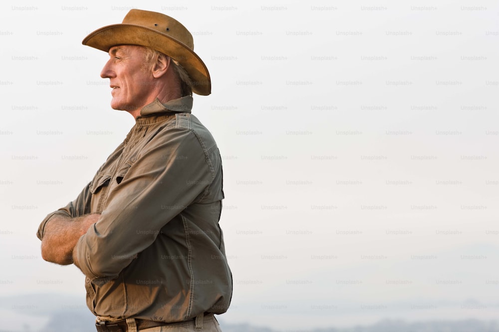 a man in a cowboy hat standing with his arms crossed