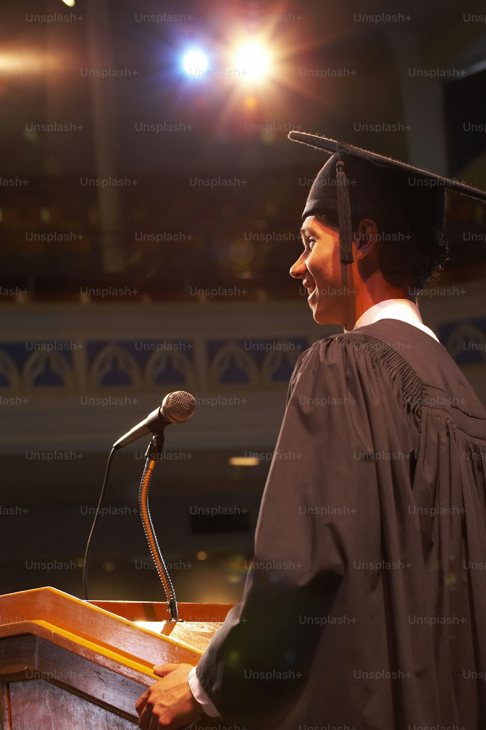 a man in a graduation gown standing at a podium