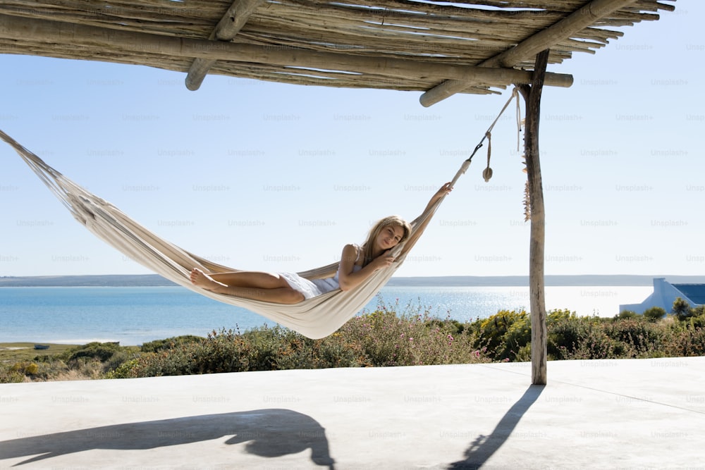 a woman laying in a hammock by the ocean
