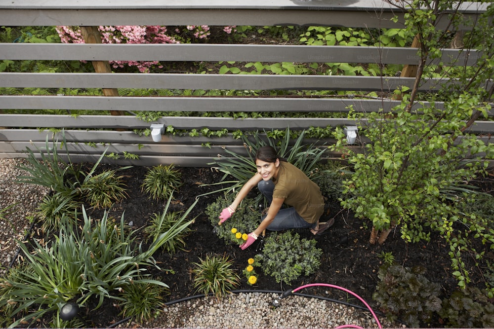 Una persona arrodillada en un jardín con plantas