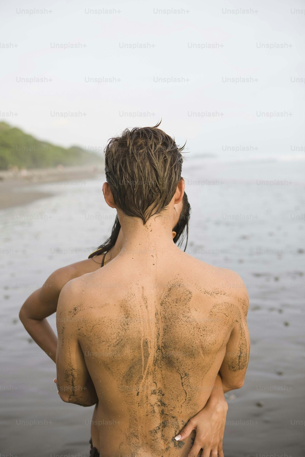 a man standing on a beach with his back to the camera