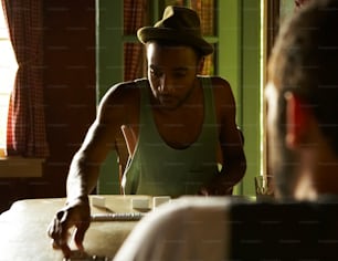 a man in a green tank top working on a laptop