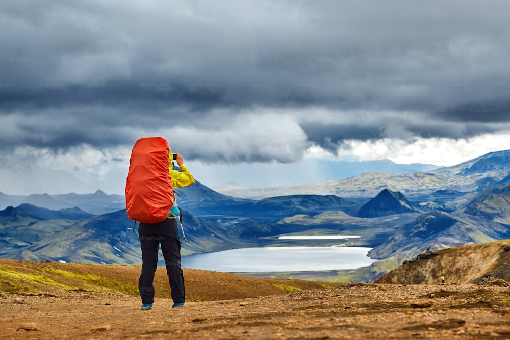 woman hiker photographer taking photo on the mountain lake background in Iceland