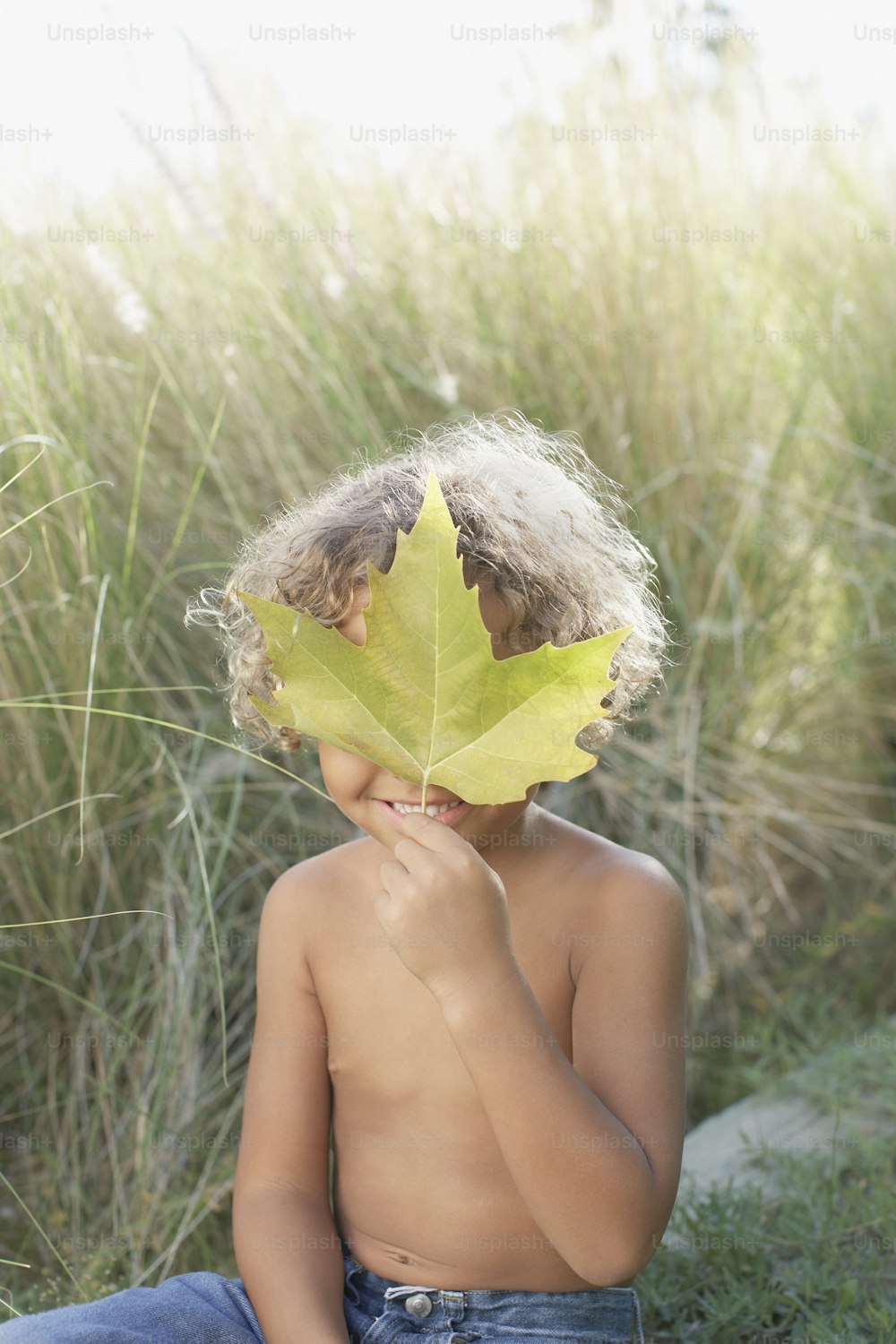 a young boy holding a leaf over his face