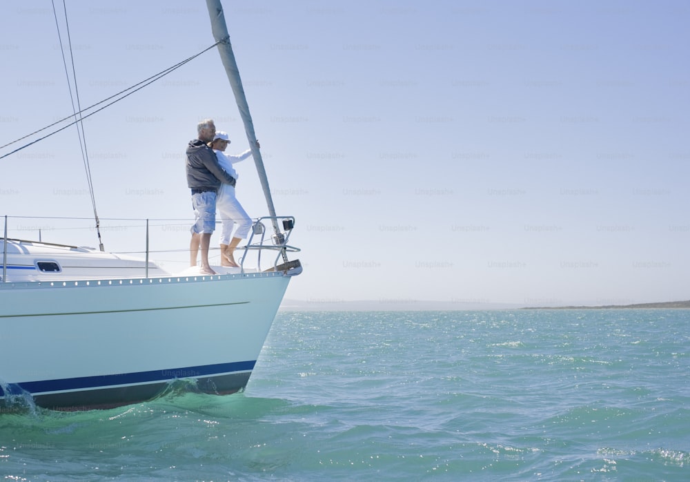 a man and woman standing on a sailboat in the ocean