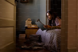 ragazza che legge riviste nella sua camera da letto di notte