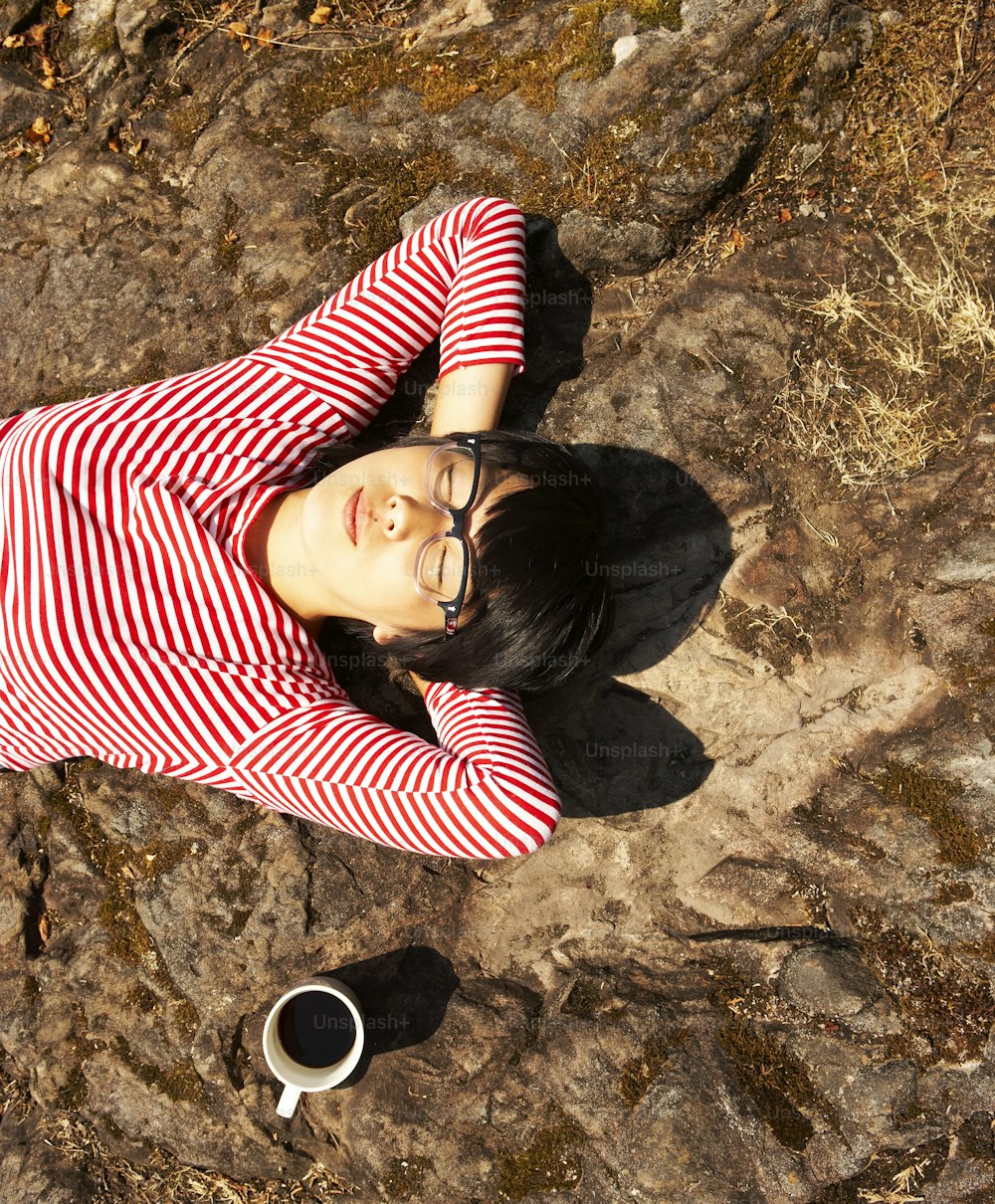a woman in a red and white striped shirt laying on a rock
