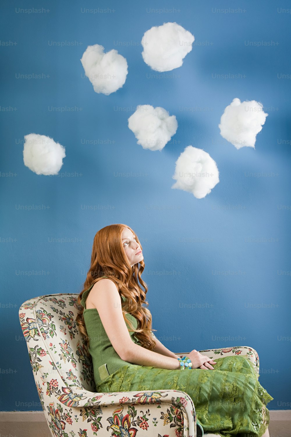 a woman sitting in a chair with clouds floating above her