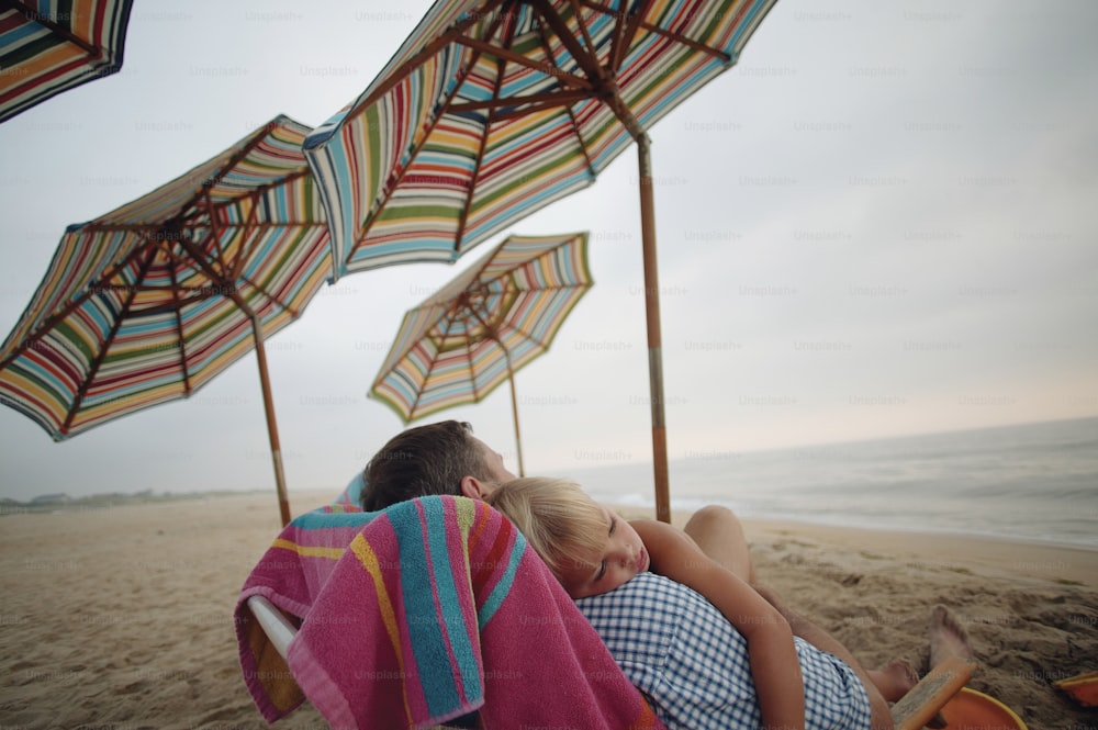 a man and a woman laying on a beach under umbrellas