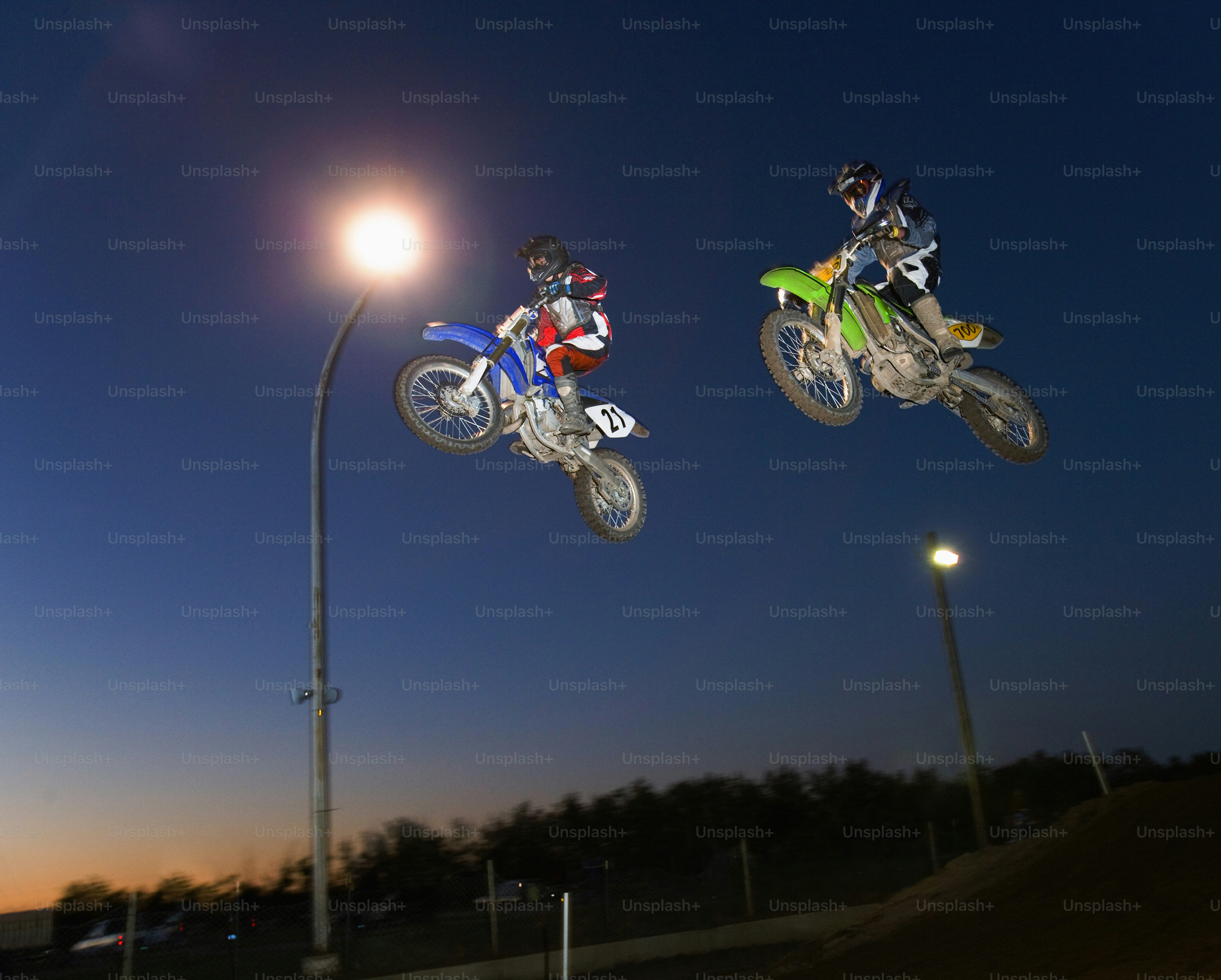 Zwei Motorradfahrer springen nachts in die Luft