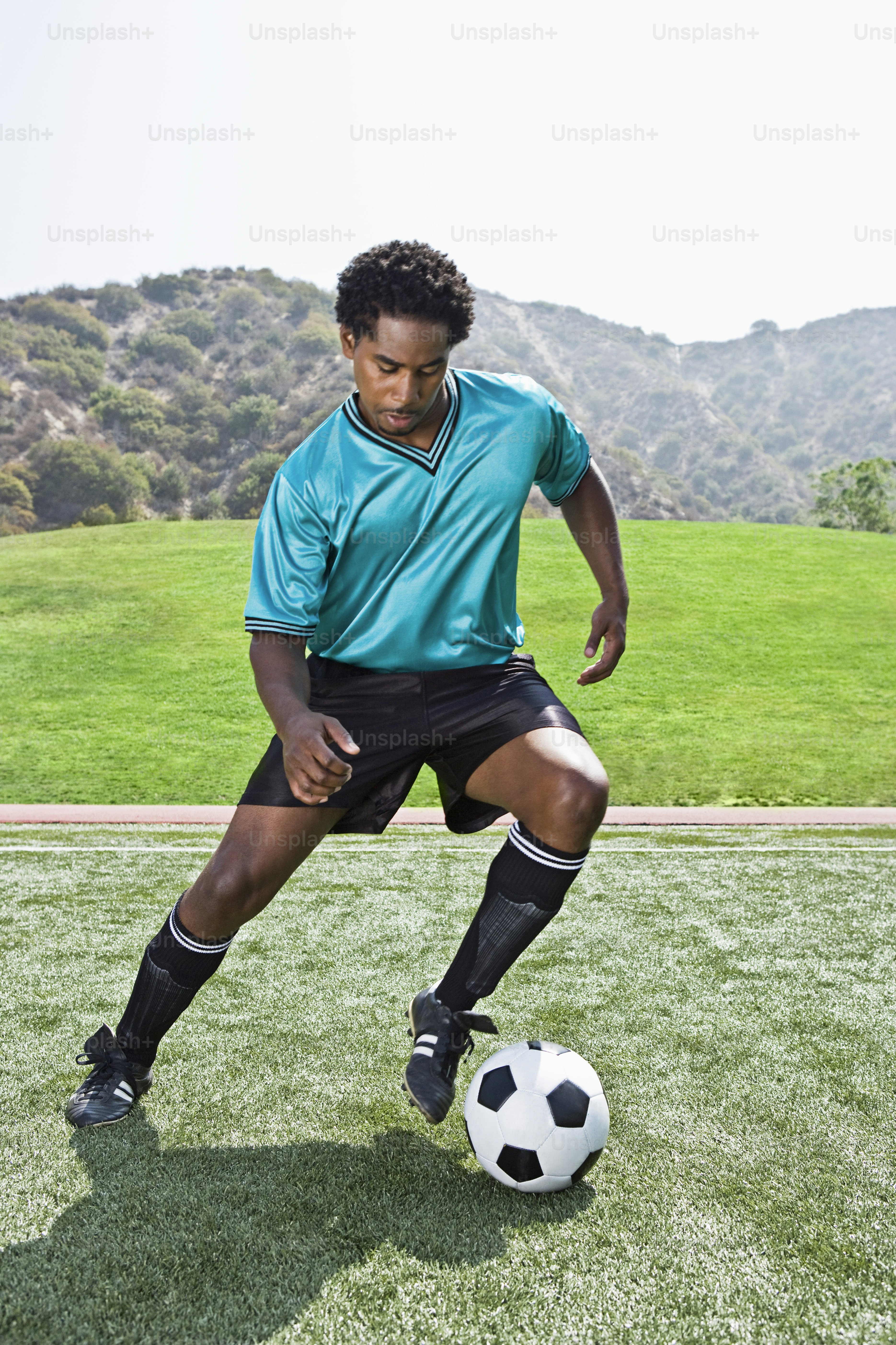 a young man kicking a soccer ball on a field