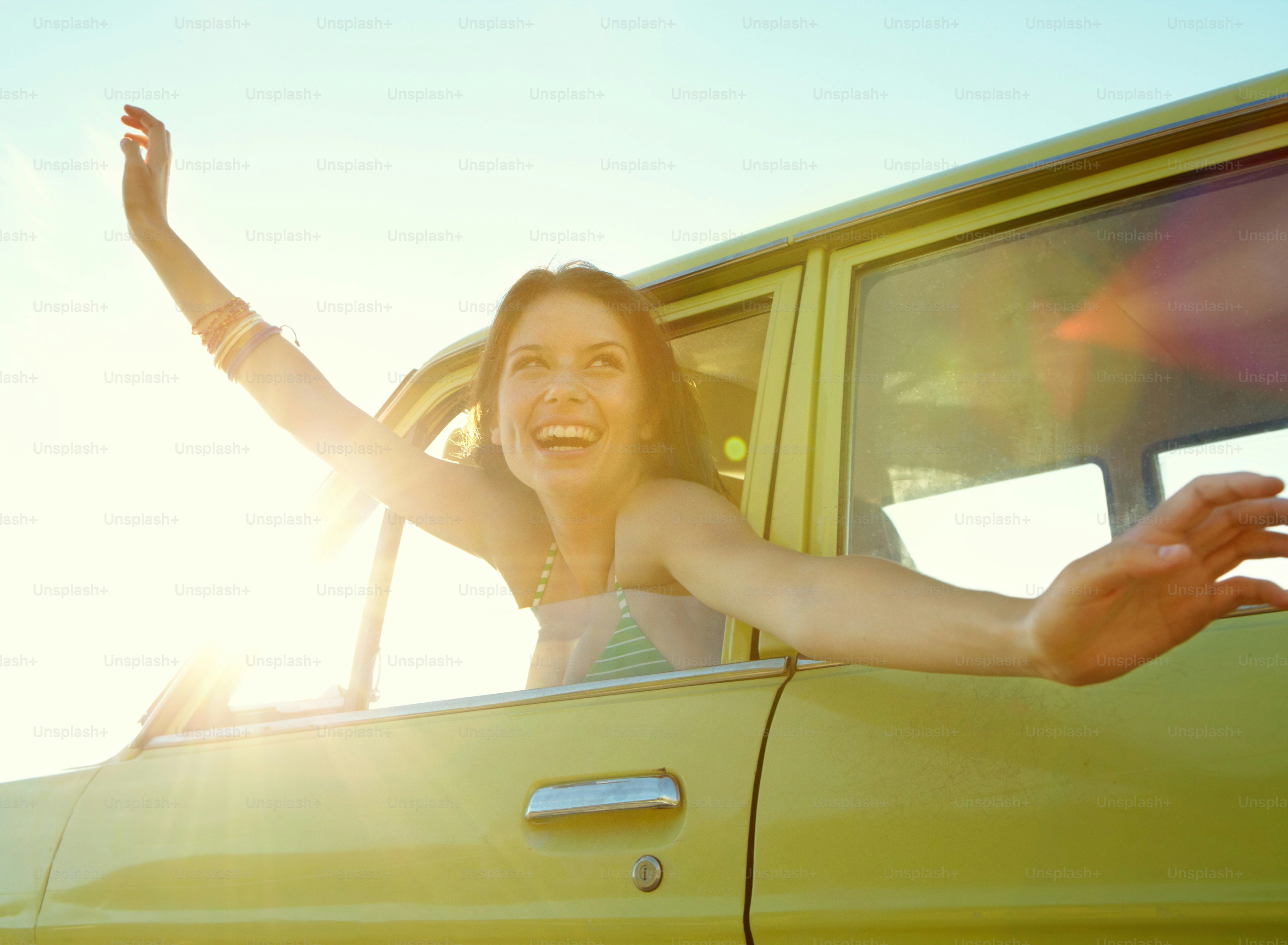 Jolie jeune femme avec ses bras tendus lors d’un voyage en voiture