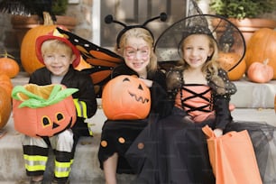 three children dressed up in halloween costumes sitting on steps