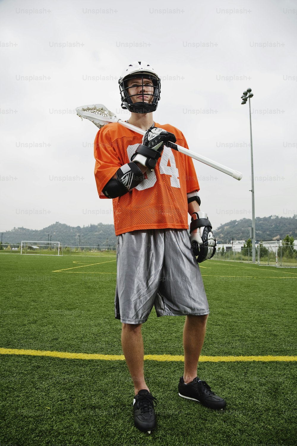a man in an orange jersey holding a lacrosse stick