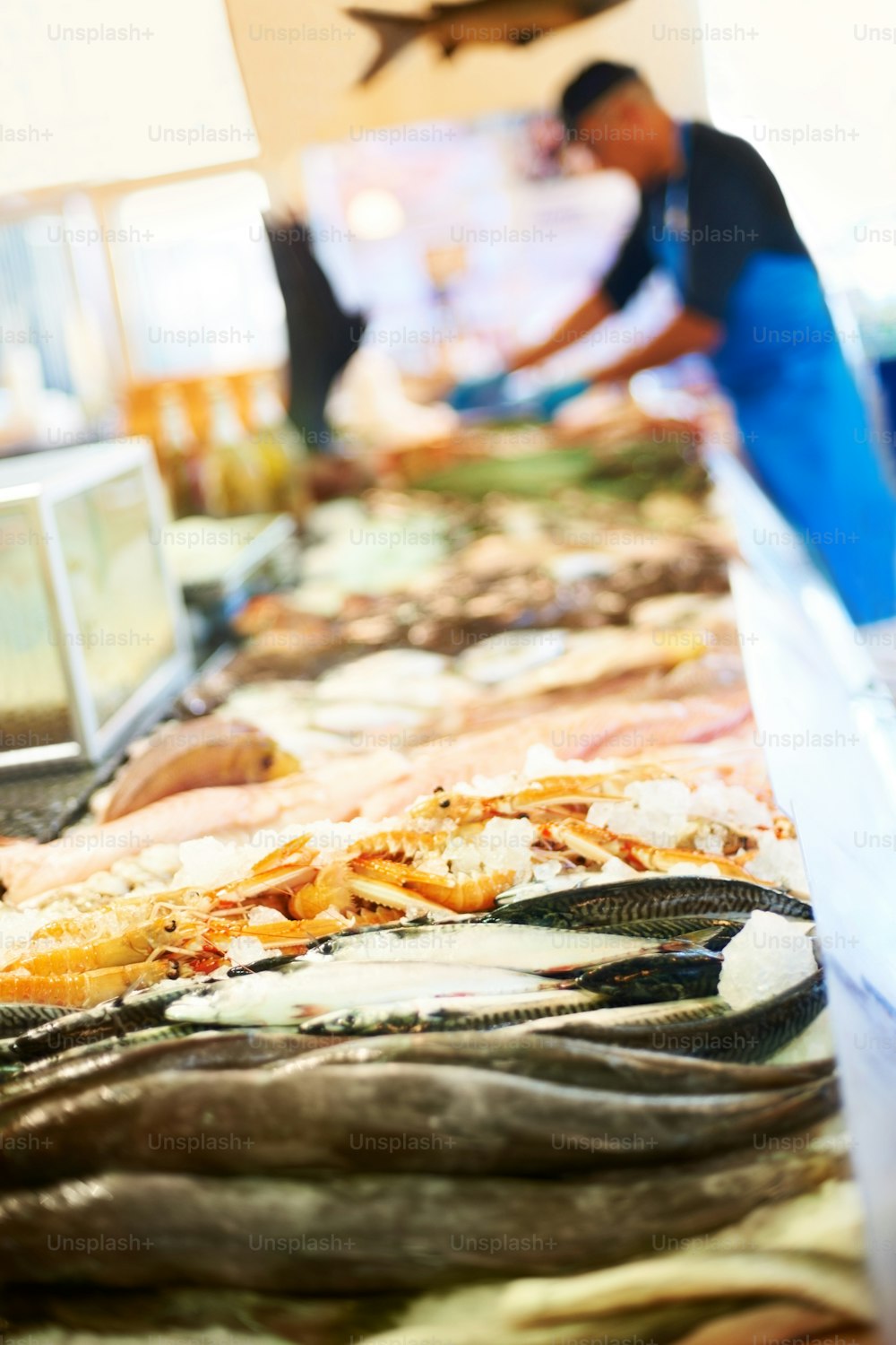 a man standing behind a counter filled with fish