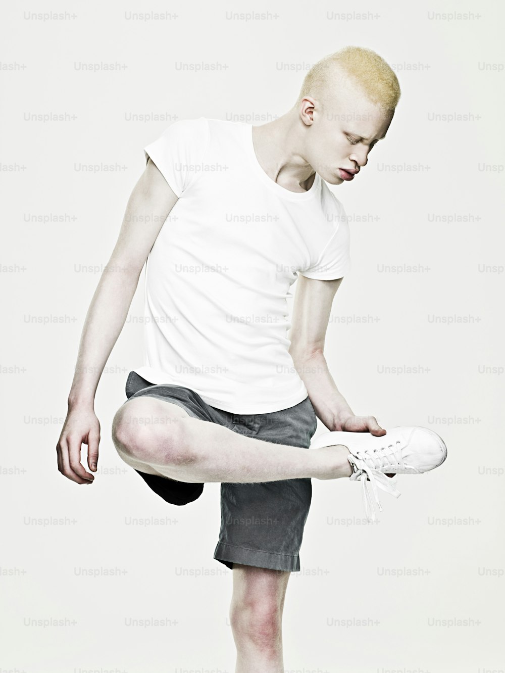 Un homme en chemise blanche et short noir tenant une chaussure blanche