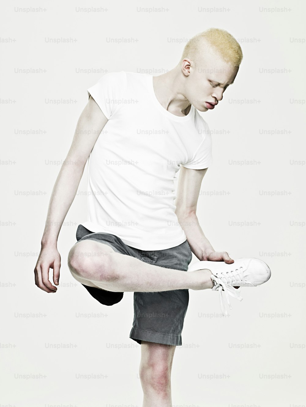a man in white shirt and black shorts holding a white shoe