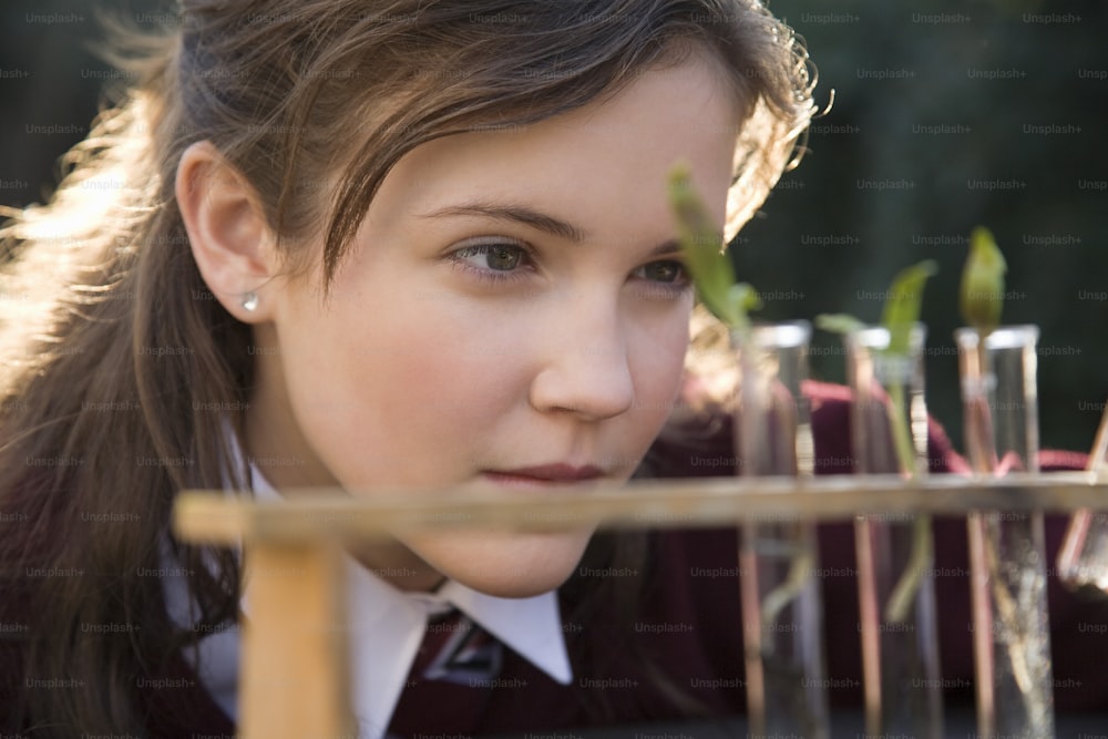 a young girl is looking at plants in a test tube