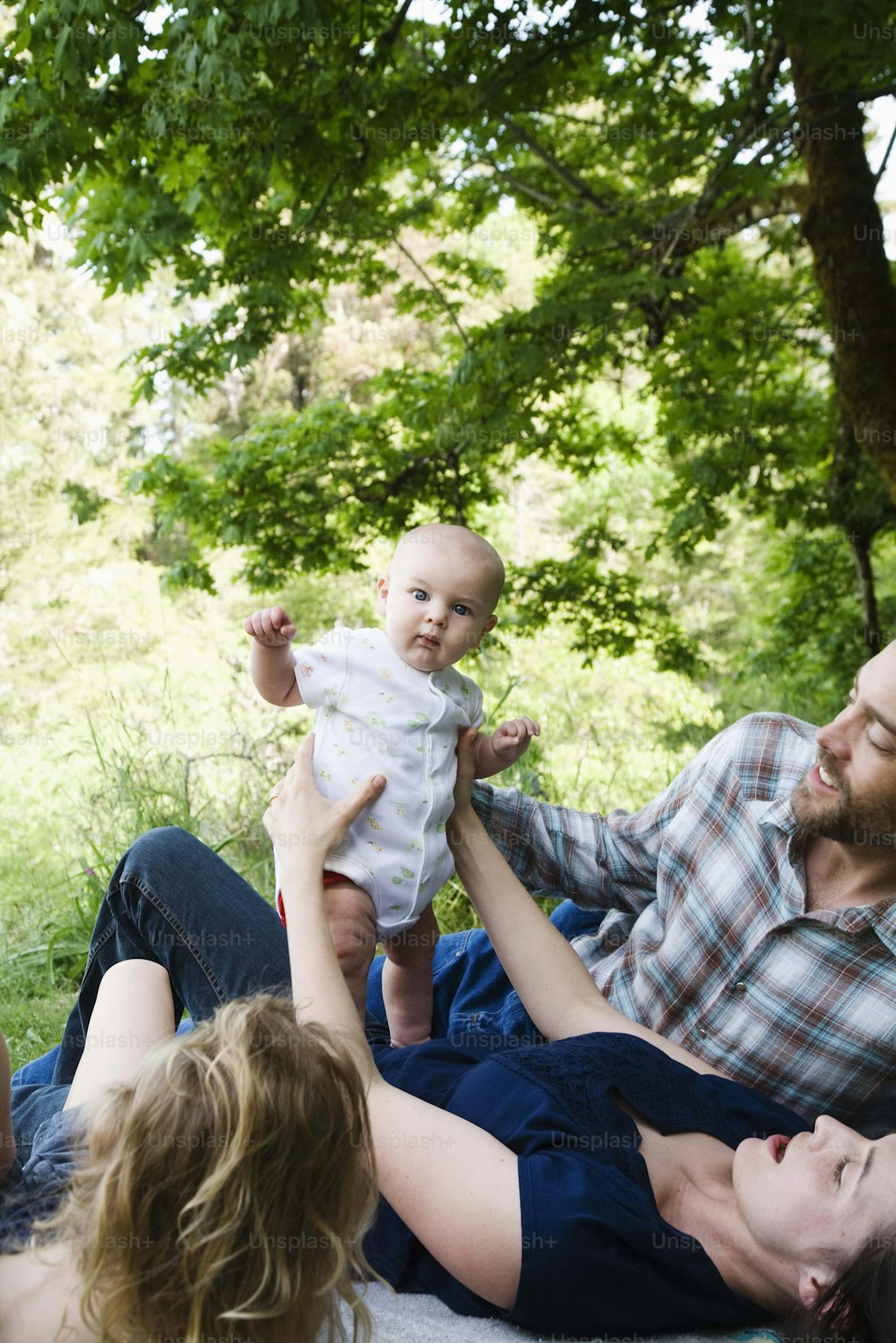 a man holding a baby while sitting on a woman's lap