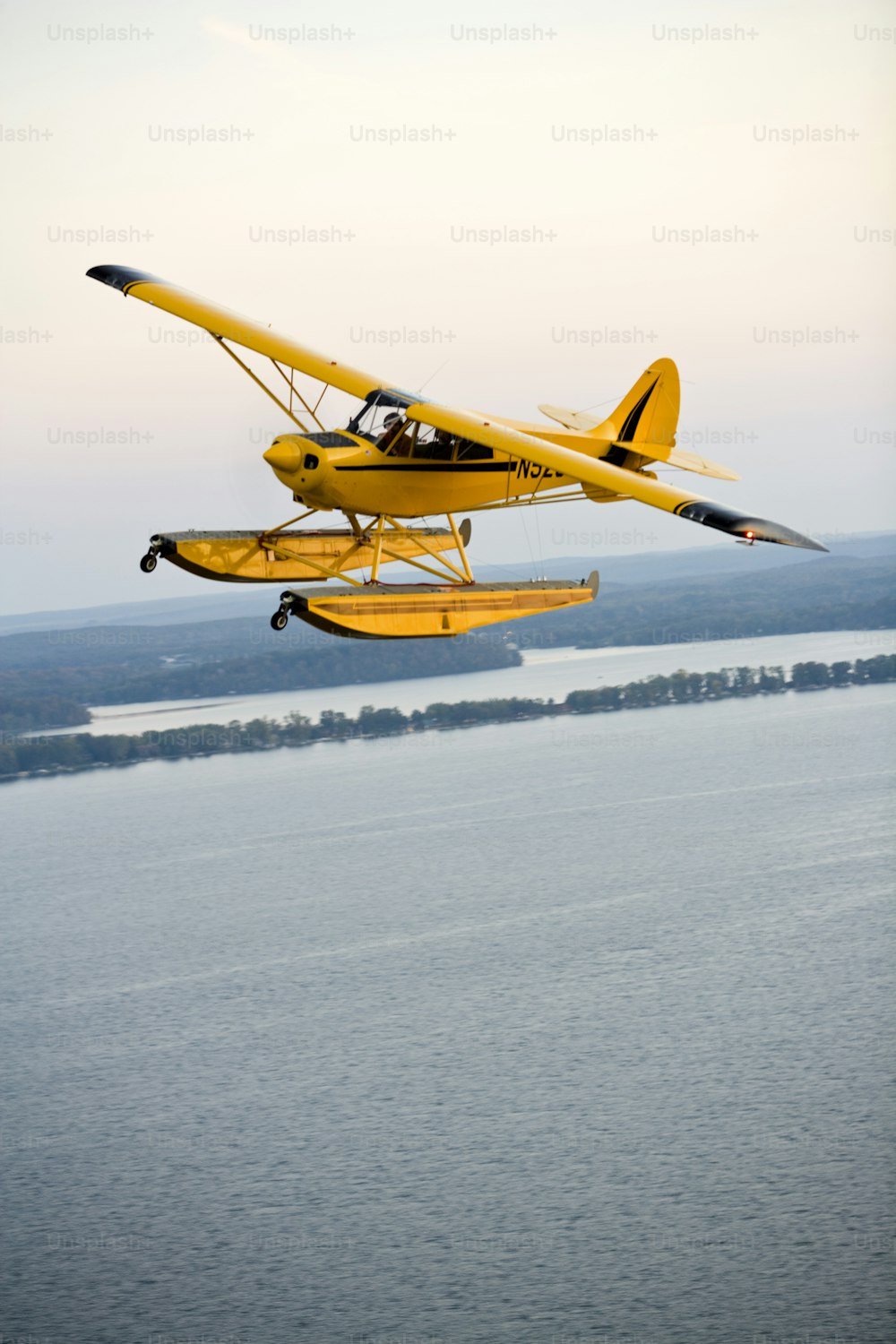 a yellow plane flying over a large body of water