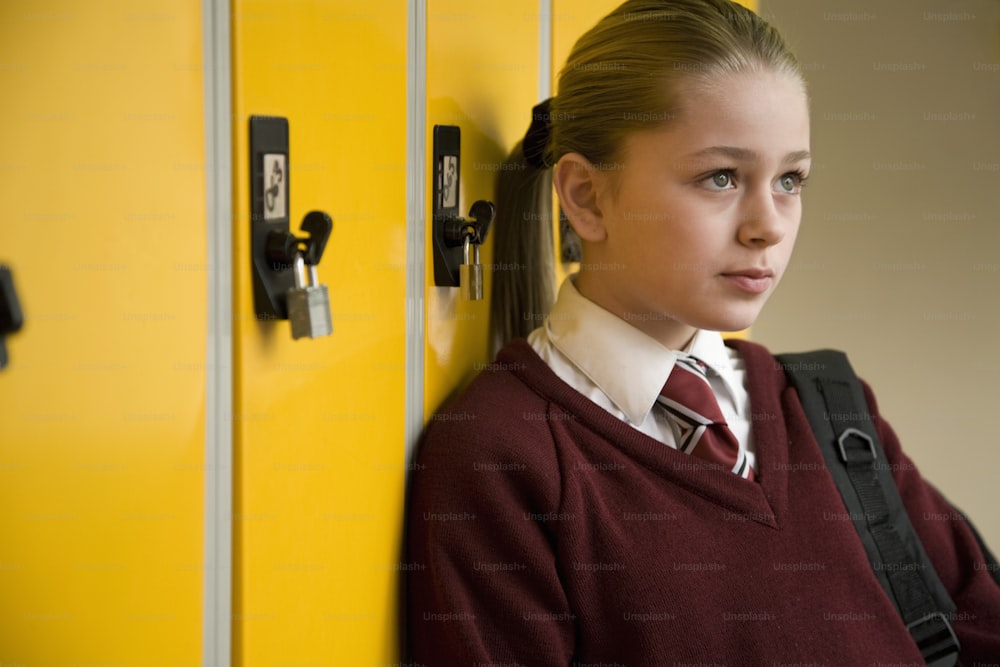 a girl in a school uniform leaning against a yellow locker