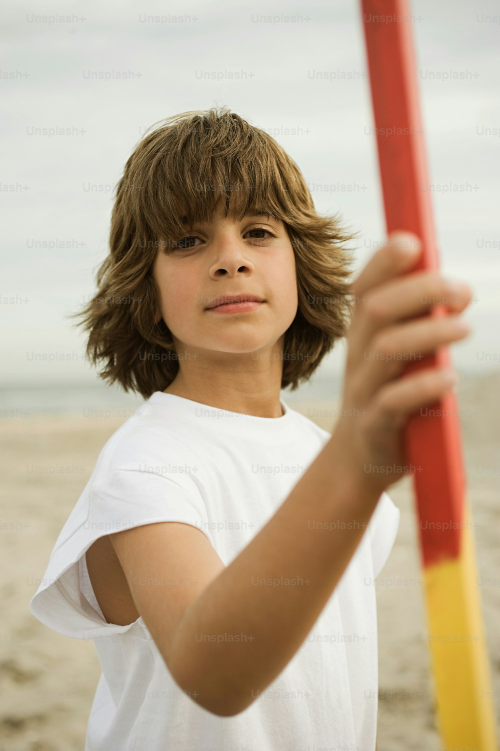 a young boy holding a red and yellow pole