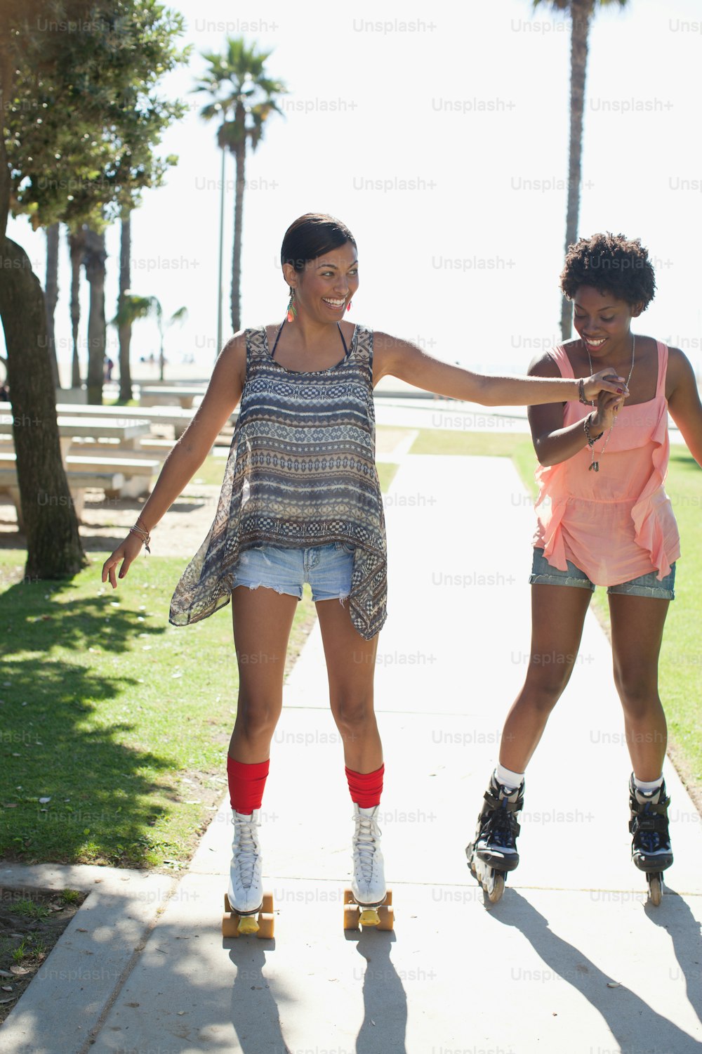 two women are rollerblading down a sidewalk