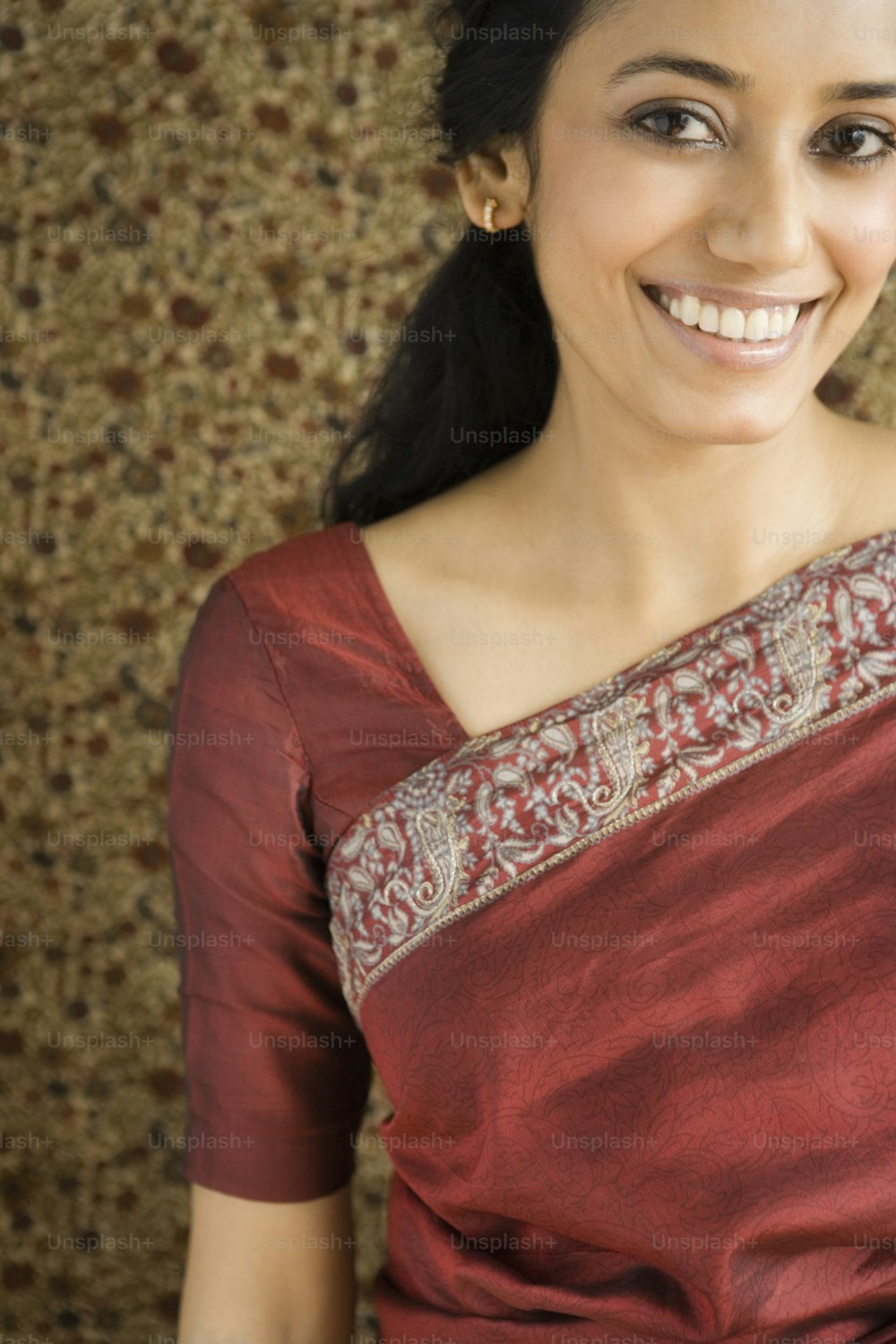 Une femme en sari rouge souriant à la caméra