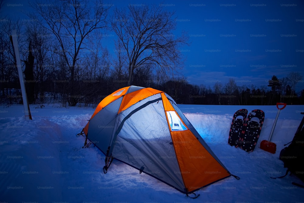 a tent pitched up in the snow at night