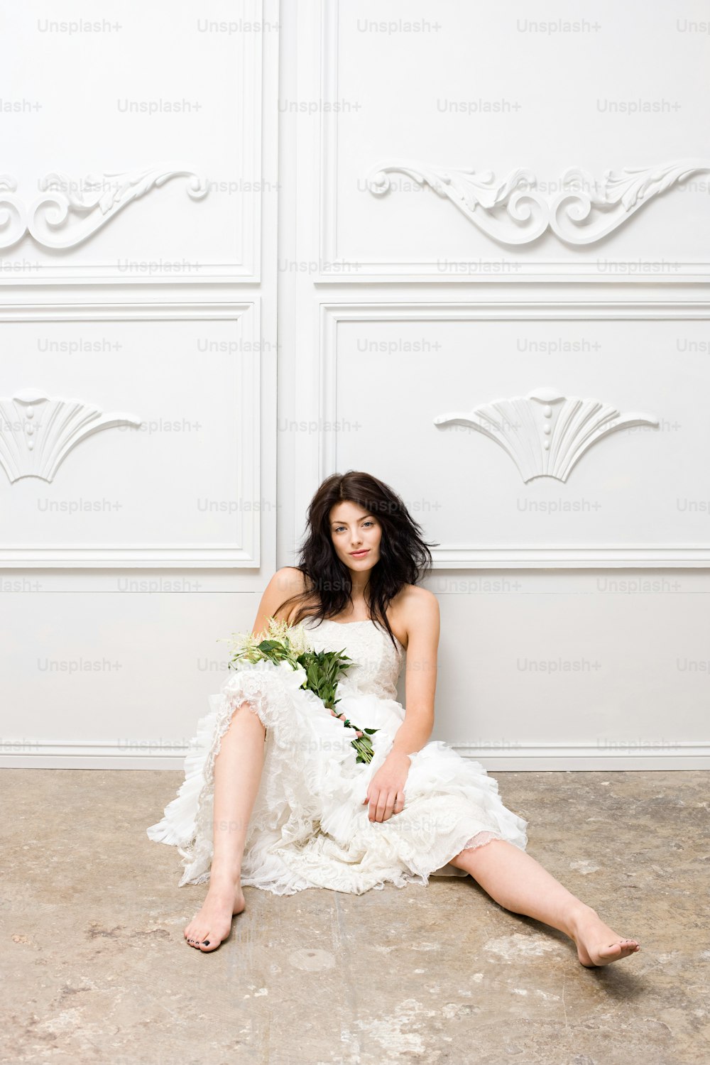 a woman in a white dress sitting on the floor