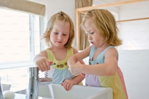 two little girls are washing their hands in the sink