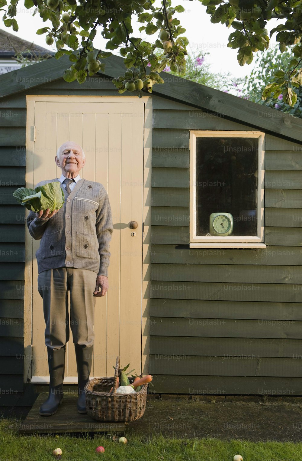 野菜を持った小屋の前に立つ男