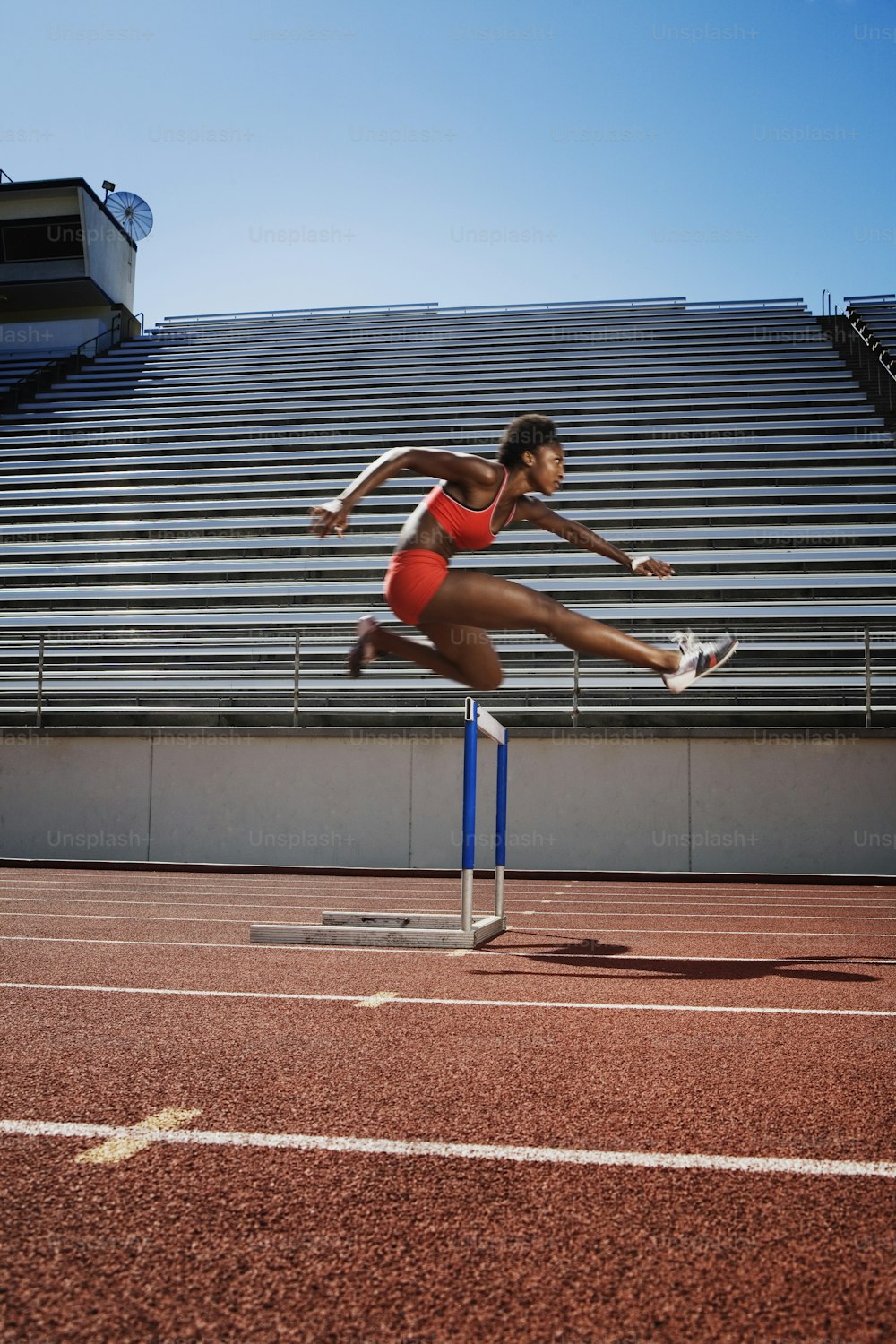 a woman jumping over a hurdle on a track