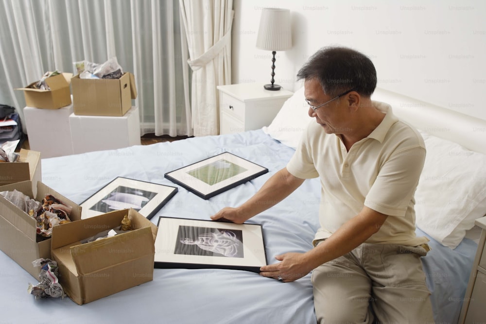 a man sitting on a bed looking at pictures