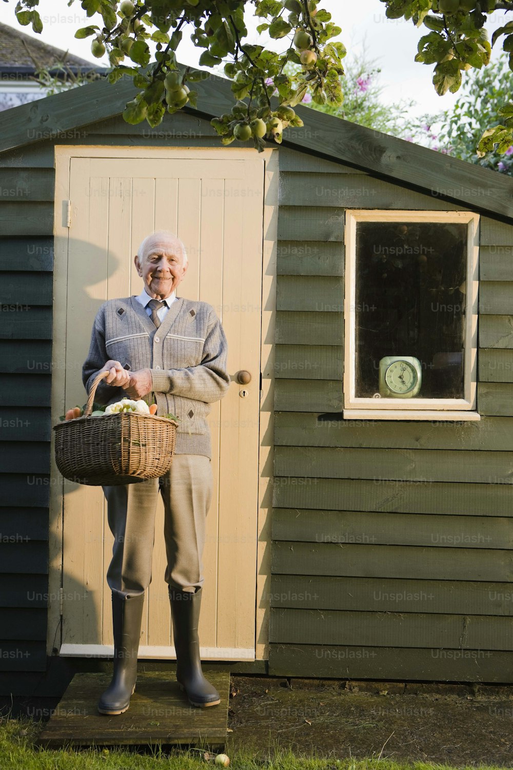 a man holding a basket standing in front of a shed