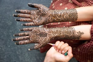 a woman with henna on her hands holding a pencil
