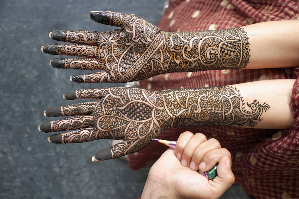 a woman with henna on her hands holding a pencil