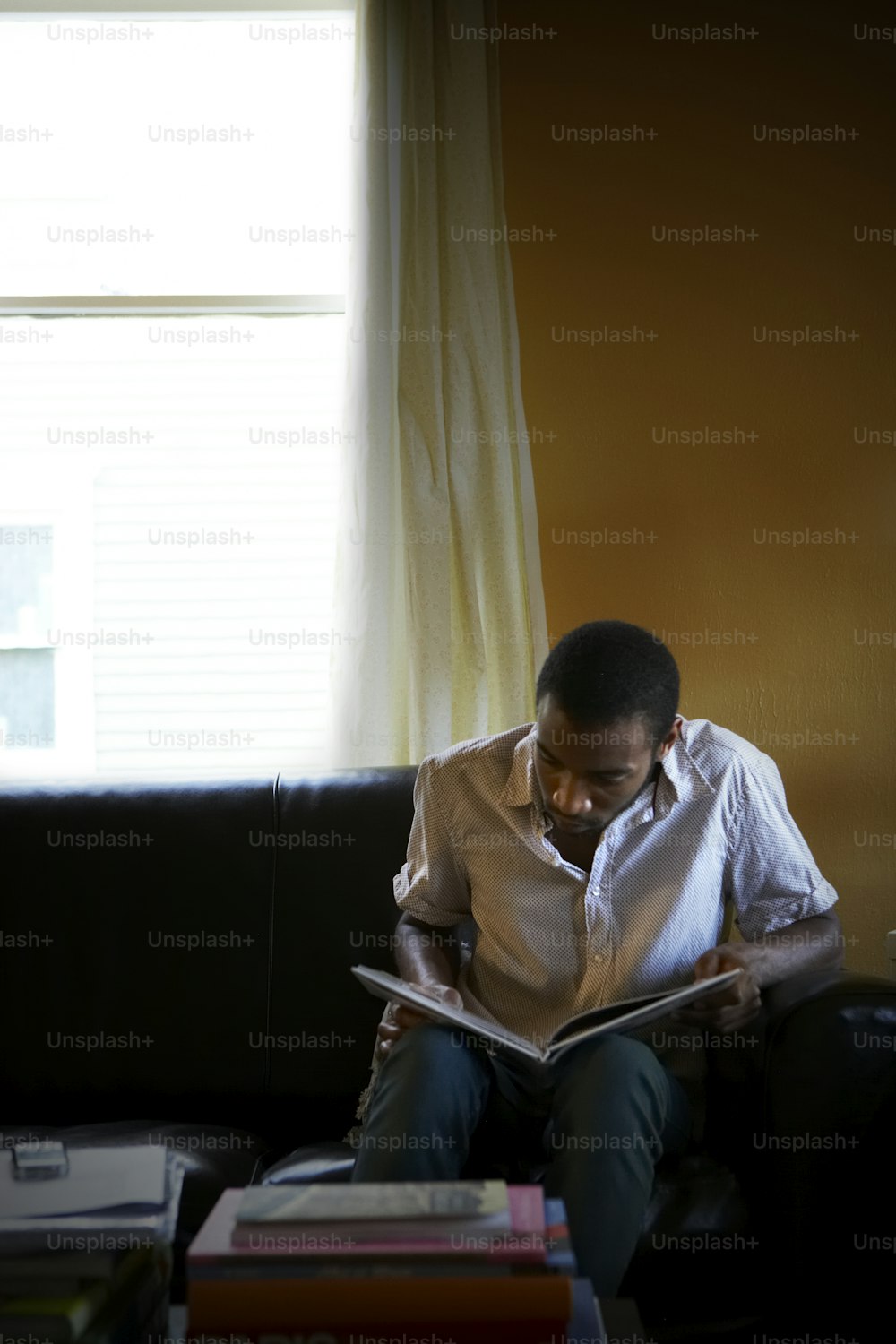 a man sitting on a couch reading a book