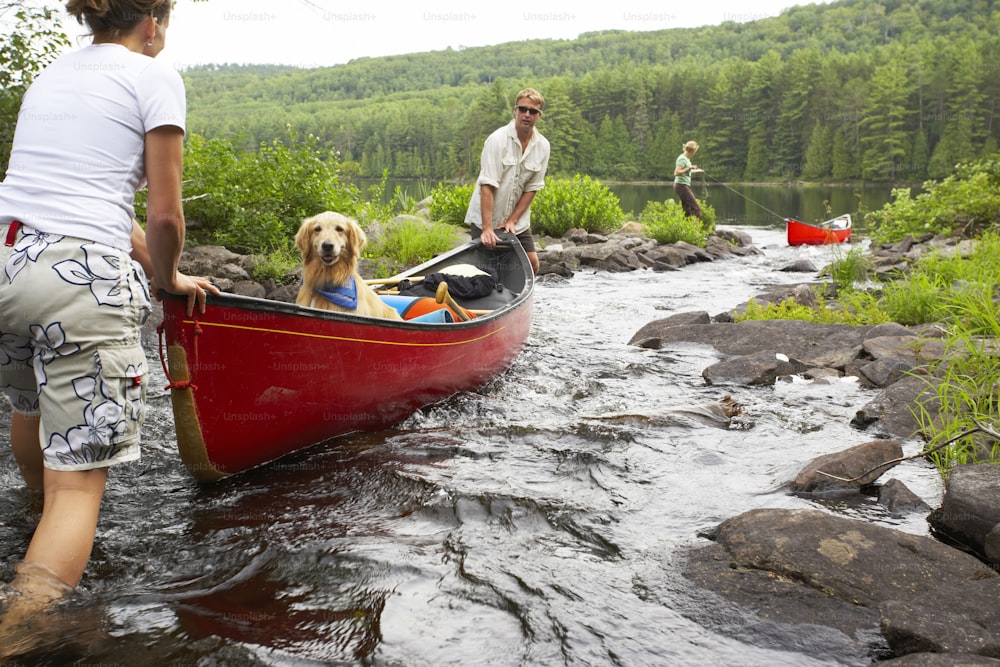a man and a woman standing next to a dog in a canoe