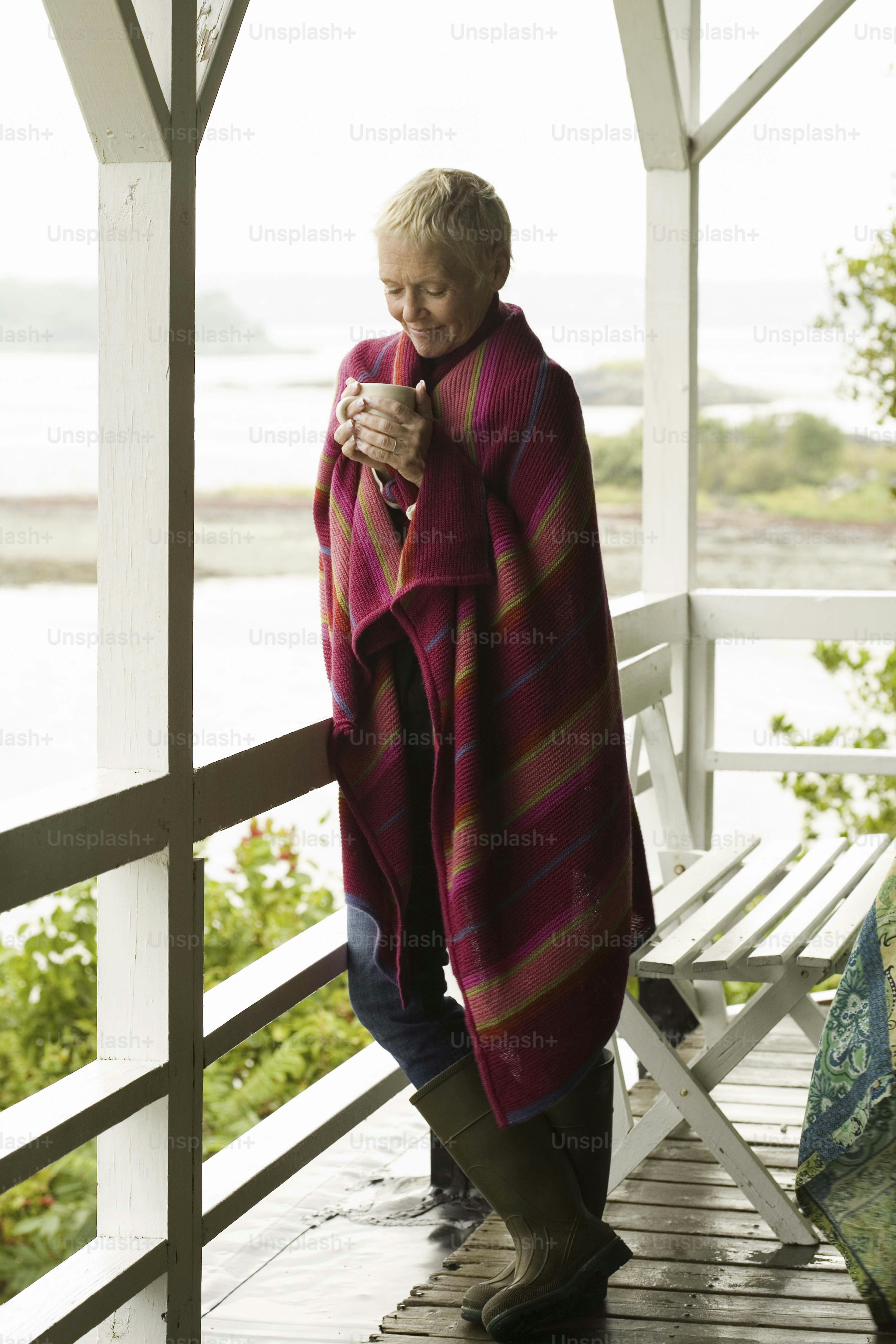 a woman standing on a porch next to a white bench