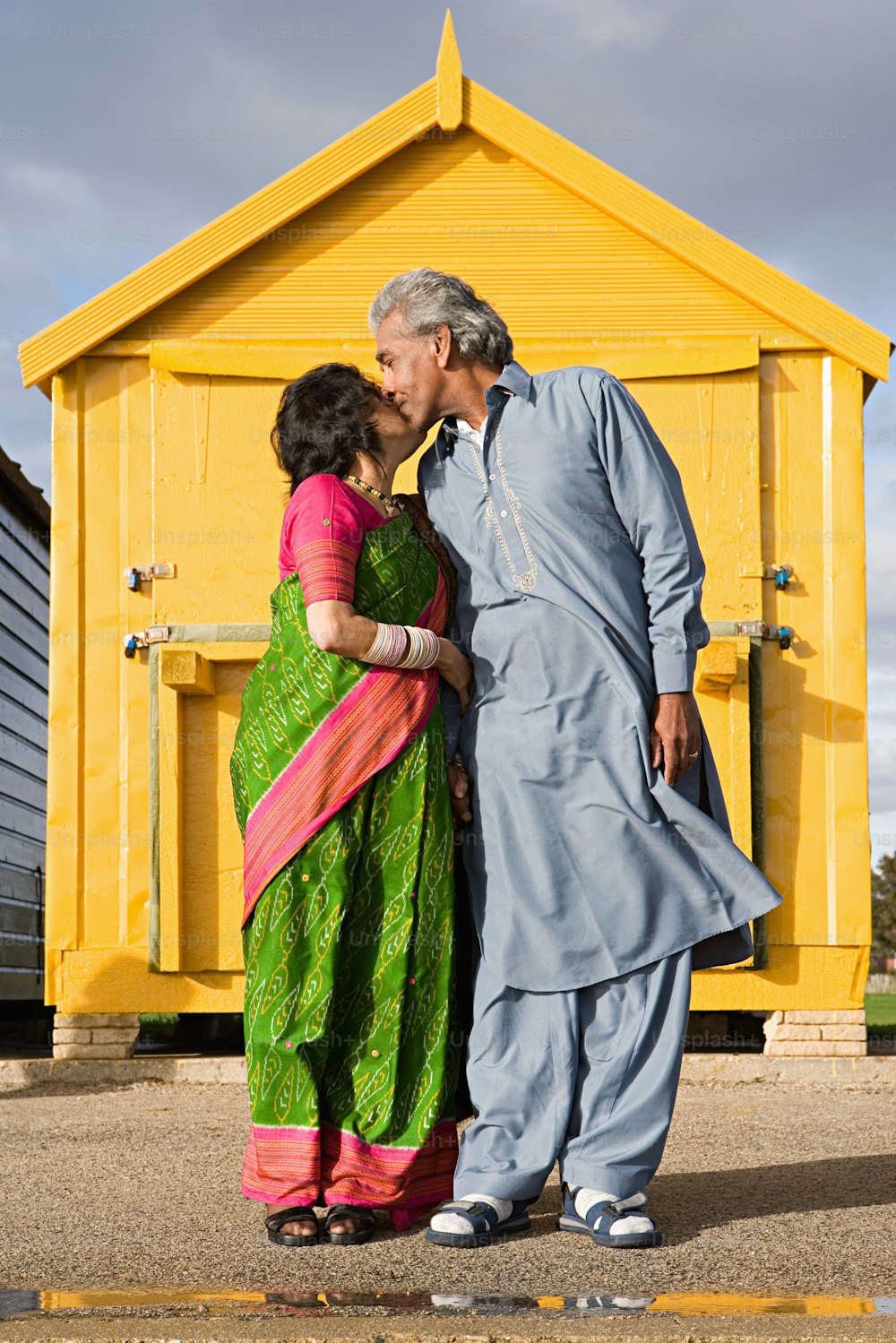 a man and a woman standing in front of a yellow building