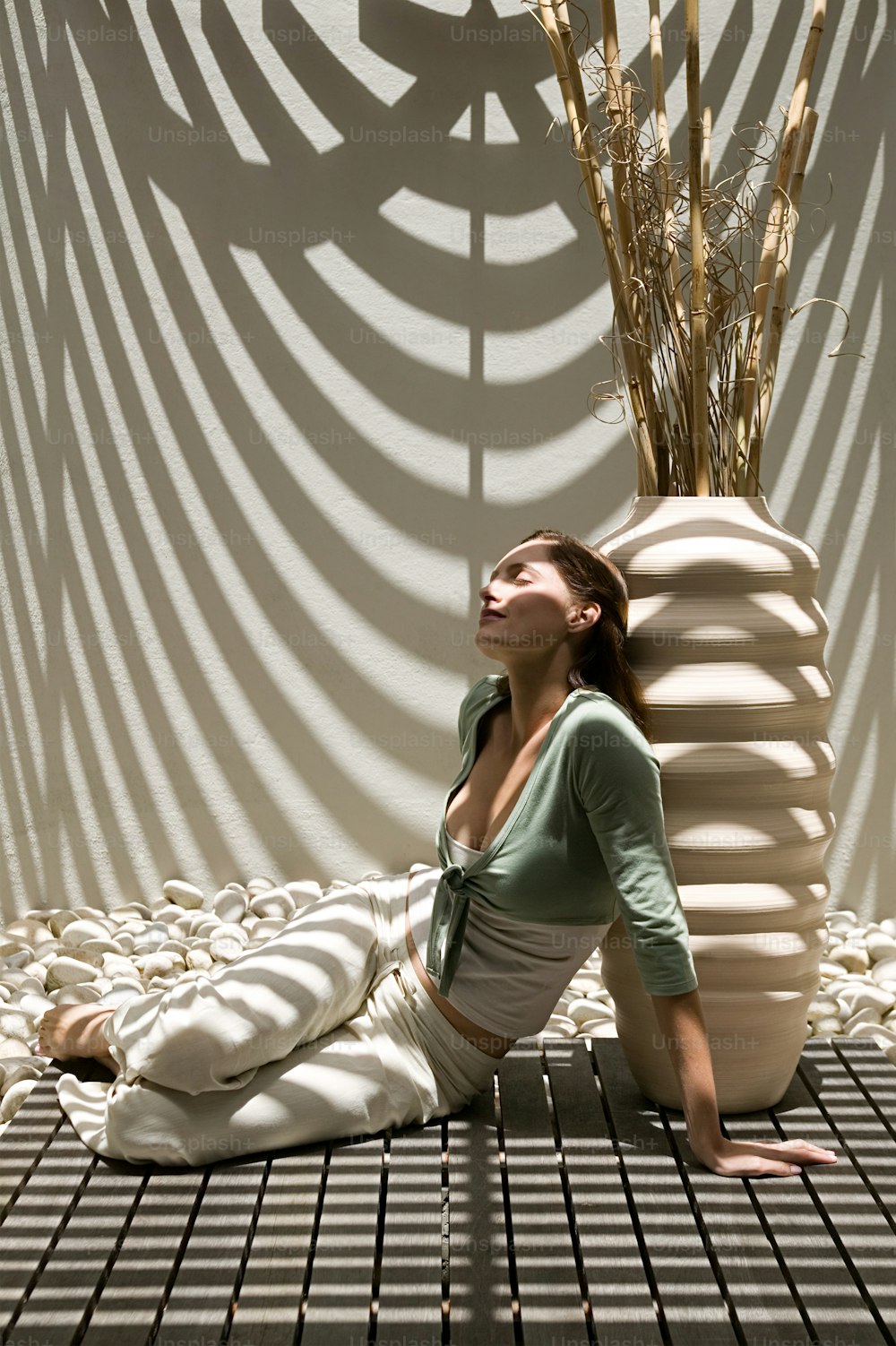 a woman sitting on the ground in front of a vase