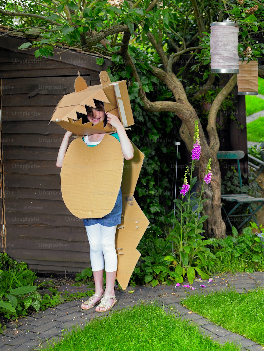 a woman standing in front of a tree holding a cardboard animal