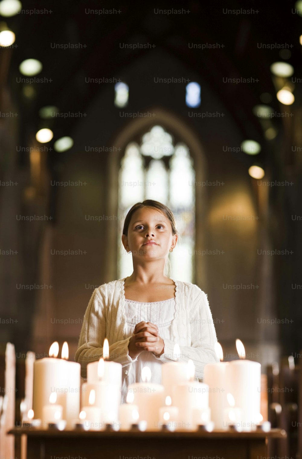 a woman standing in front of a bunch of lit candles
