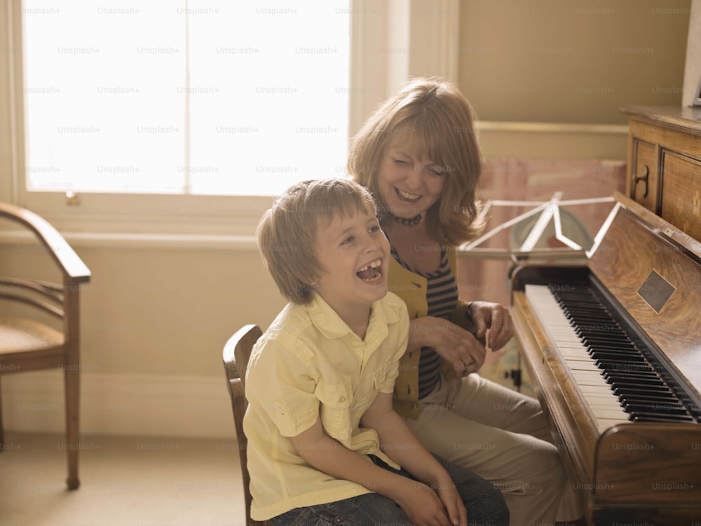 a woman sitting next to a child at a piano