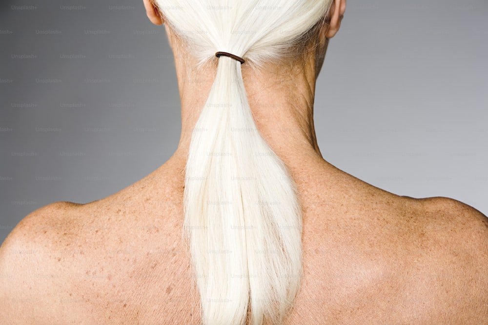 la parte posterior de la cabeza de una mujer con cabello largo y blanco