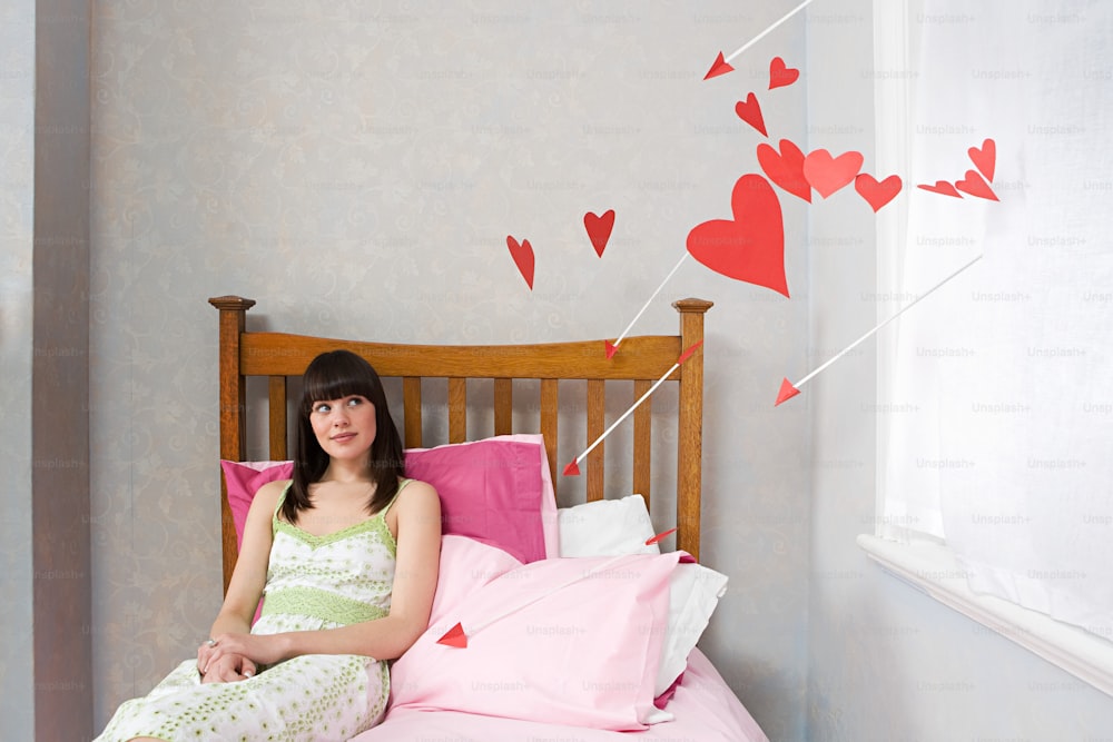 a woman sitting on a bed with pink sheets