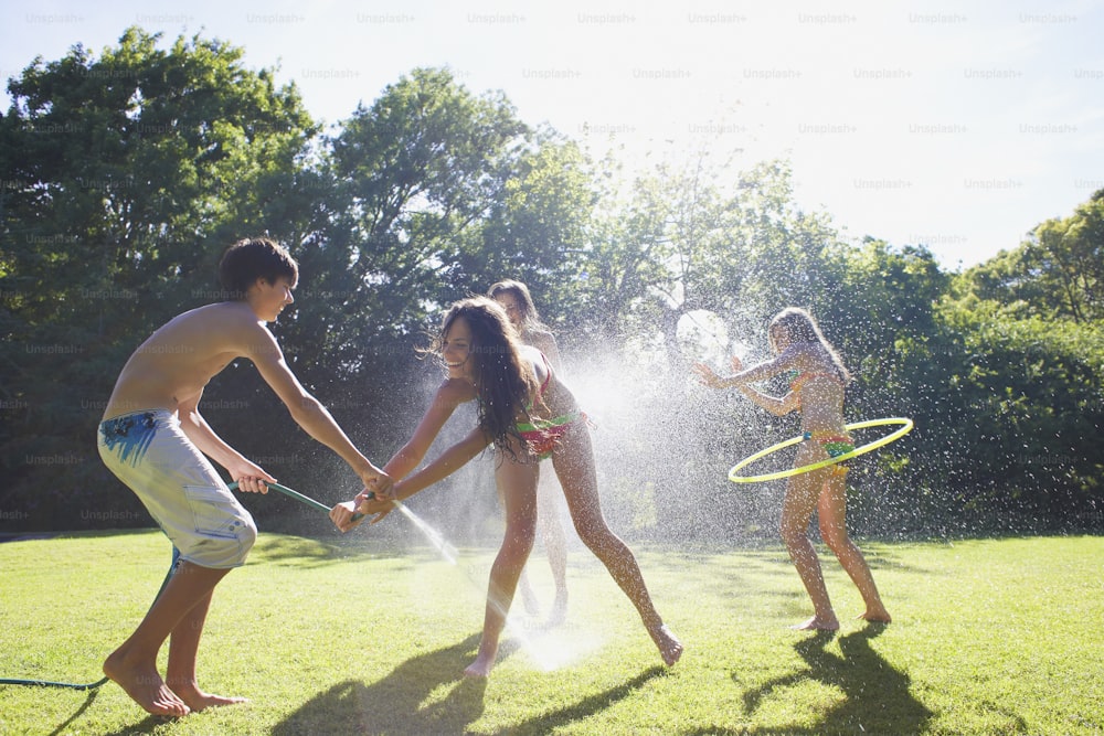 a group of young people playing with a sprinkler