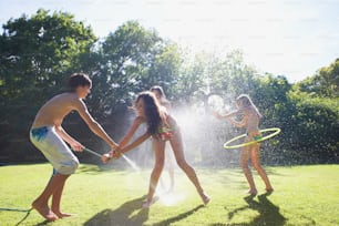 a group of young people playing with a sprinkler